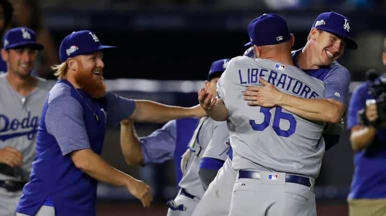 Dodgers relief pitcher Adam Liberatore is hugged by a teammate...