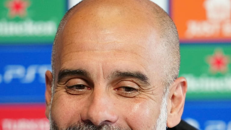 Manchester City's head coach Pep Guardiola smiles as he speaks...