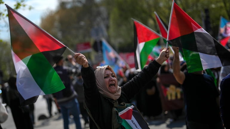A woman waves flags in support of Palestinians in Gaza...