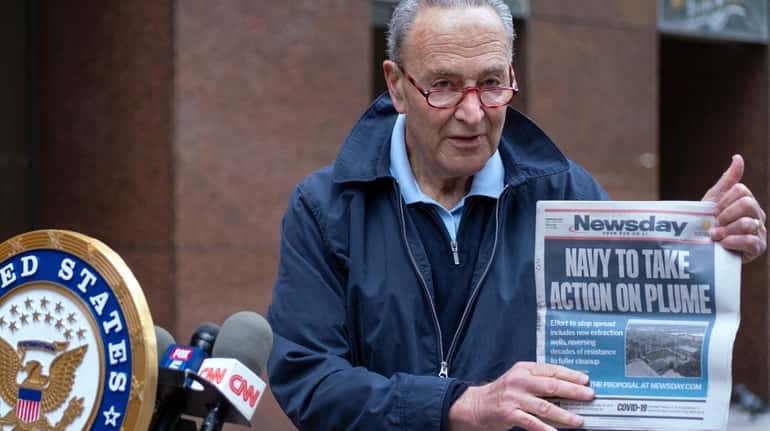 Sen. Chuck Schumer holds up a copy of Newsday while...