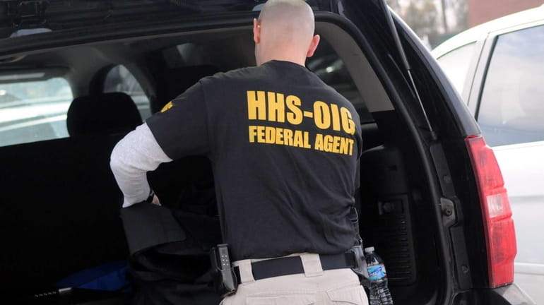 A federal agent removes evidence Tuesday, March 11, 2014, from...
