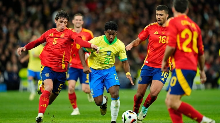 Brazil's Endrick, centre, tries to get past Spain's Robin Le...