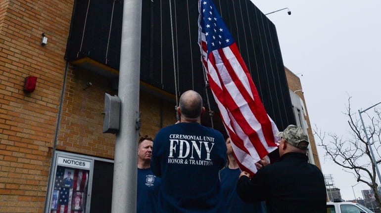 Firefighters set the flag to half-staff in front of Ladder Company...