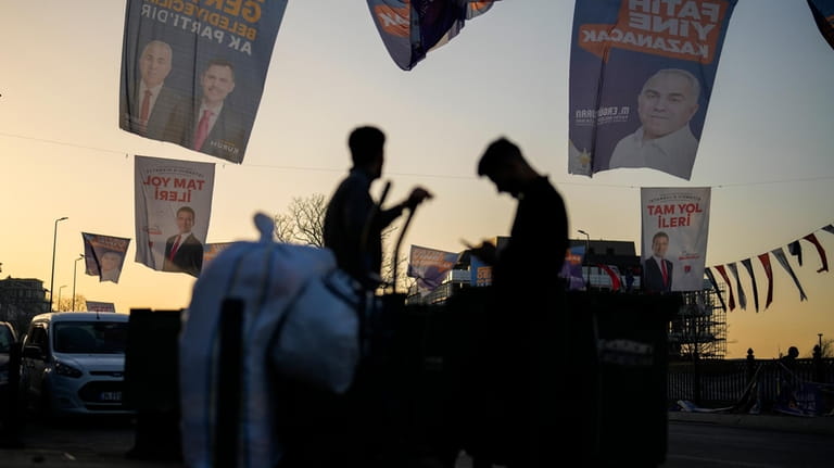 People walk under campaign banners of candidates for Istanbul of...