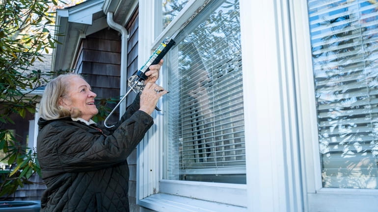 Caroline Riley uses removable caulking to seal drafty windows at her Cutchogue...