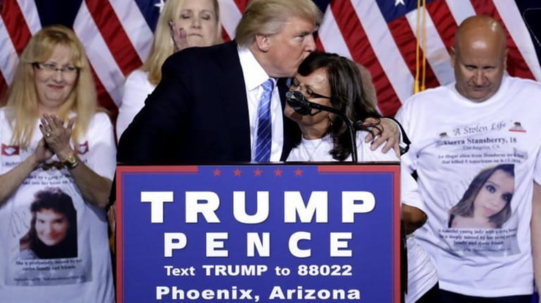 Republican presidential candidate Donald Trump hugs a woman, whose child...