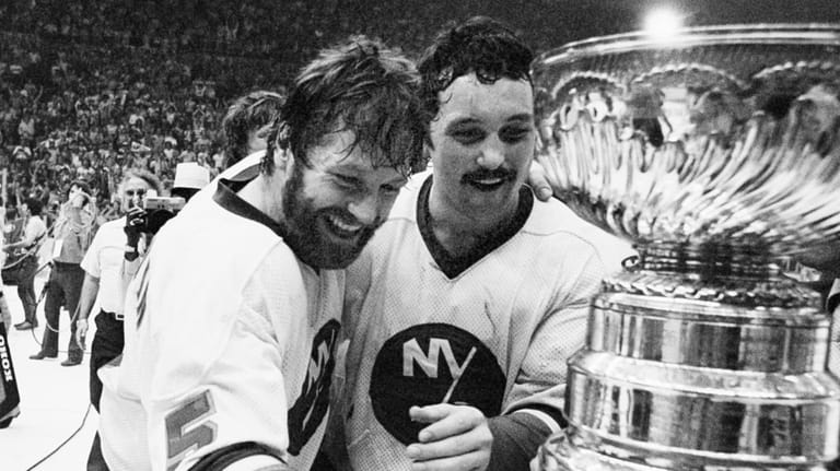 New York Islanders captain Denis Potvin (5) reaches out to...