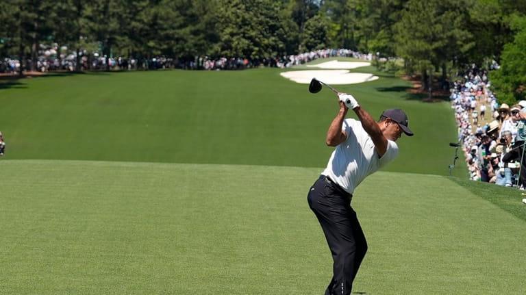 Tiger Woods hits his tee shot on the first hole...