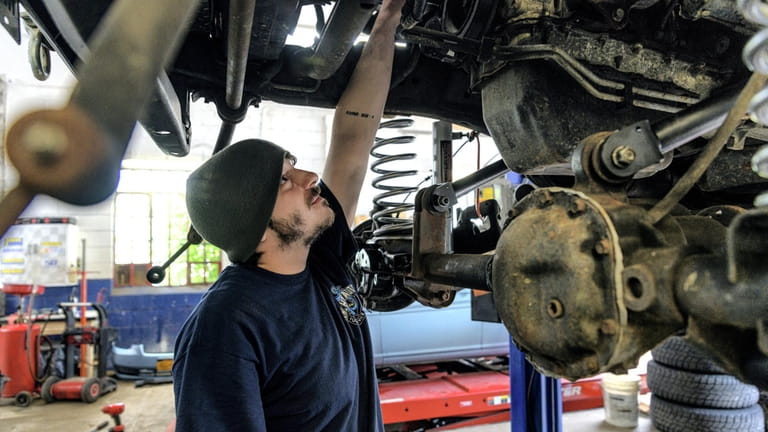 Mechanic Brandon Joyce, of Mastic Beach, works on a car...