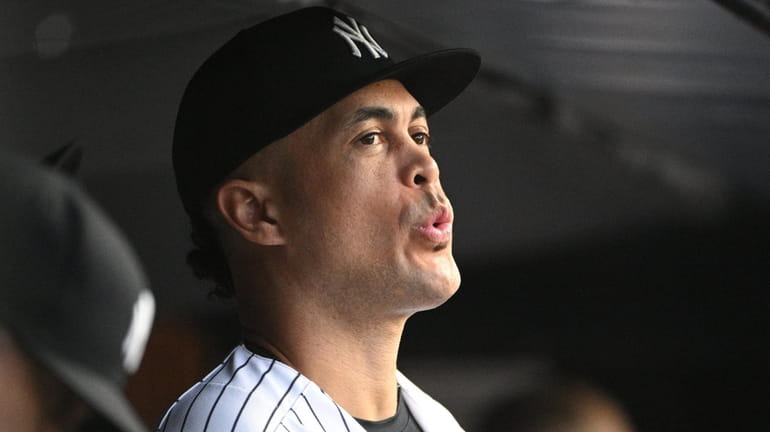The Yankees' Giancarlo Stanton looks on from the dugout during...