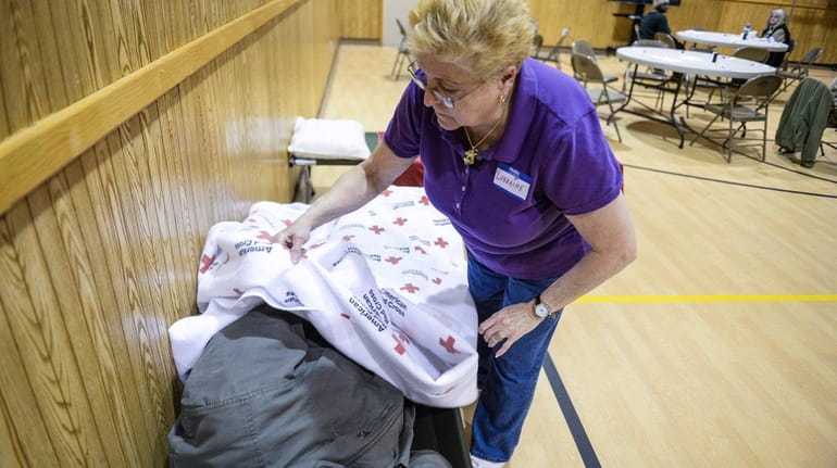 Volunteer Lorraine DeMarchis covers up a man sleeping in the...