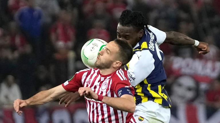 Olympiacos' Kostas Fortounis, left, and Fenerbahce's Bright Osayi-Samuel jump for...