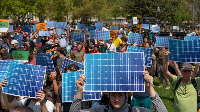 Activists display prints replicating solar panels during a rally to...