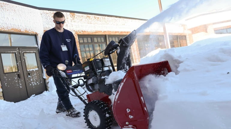 Andrew Casey, 19, of Rocky Point, uses a snowblower to...
