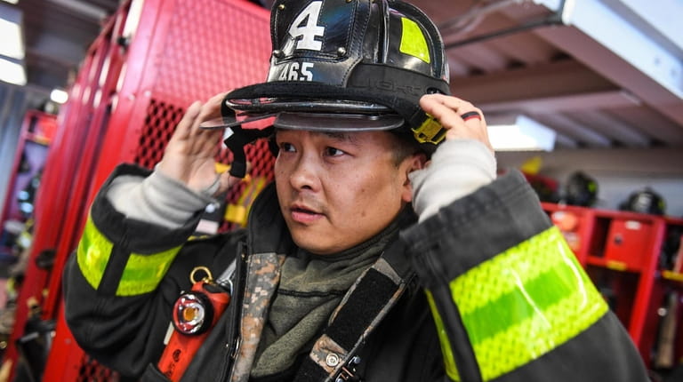 Bo Tian, of Syosset Fire Department, puts his gear on...
