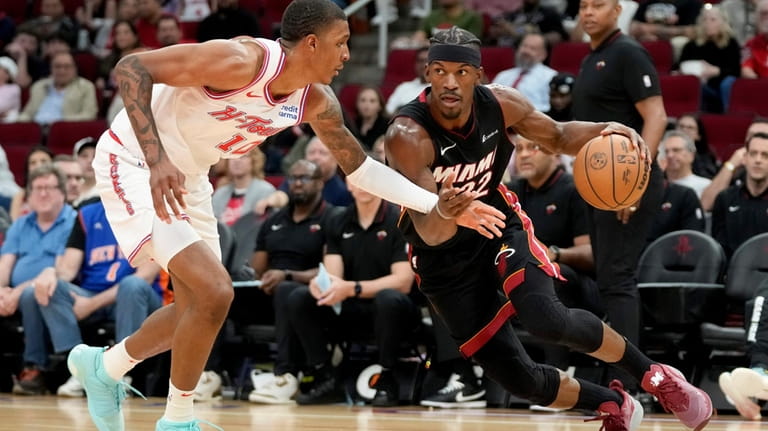 Miami Heat forward Jimmy Butler, right, dribbles the ball as...