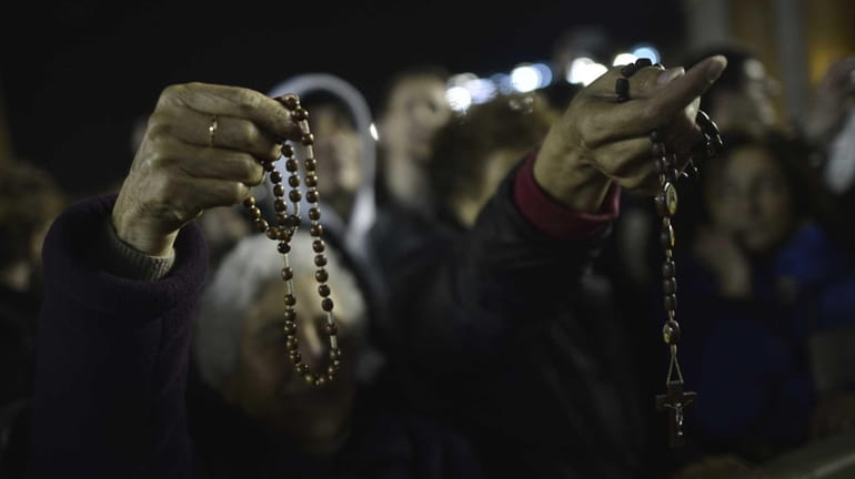 Women hold rosaries at St Peter basilica during the conclave...