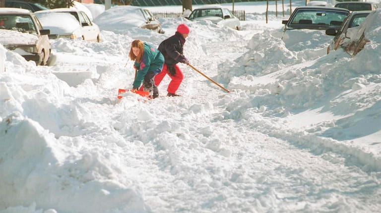 Annie, 13, and Katie, 10, attempt to shovel out their...