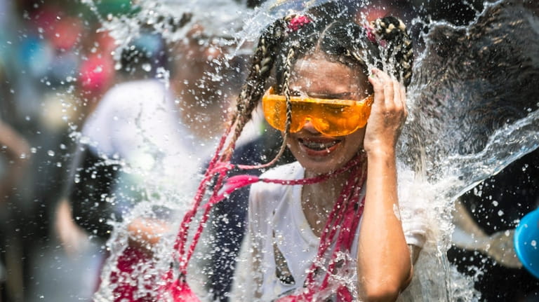 A woman reacts as a bucket of water is splashed...