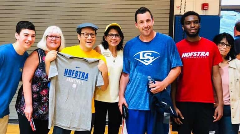 Comedian Adam Sandler, center in blue shirt, played basketball Thursday at Hofstra University before...