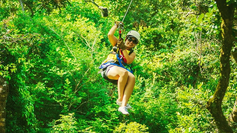 A woman takes a canopy zipline tour between trees in Costa Rica.