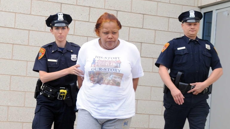 Police escort Kutima Glover, 33, of Huntington Station, out of...