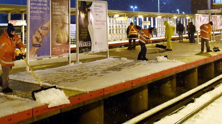 Workers shovel snow at the Ronkonkoma LIRR station on Monday...