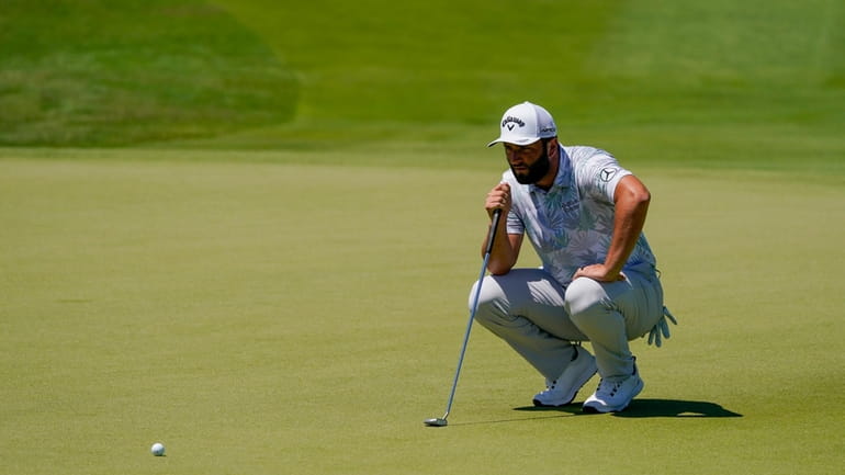 Jon Rahm, of Spain, lines up a putt on the...