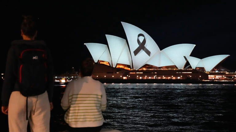 People look as the Sydney Opera House is illuminated with...