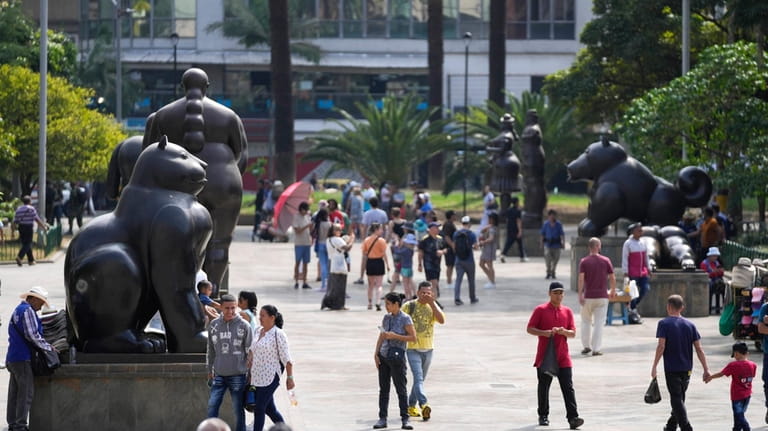 Visitors walk through Botero Plaza in Medellin, Colombia, Thursday, Feb....