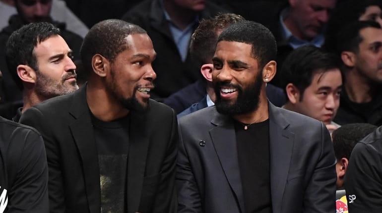 Kyrie Irving, right, chats with teammate Kevin Durant on the Nets...
