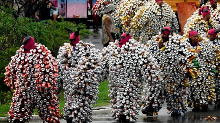Revelers wearing costumes made from beer and soda cans take...