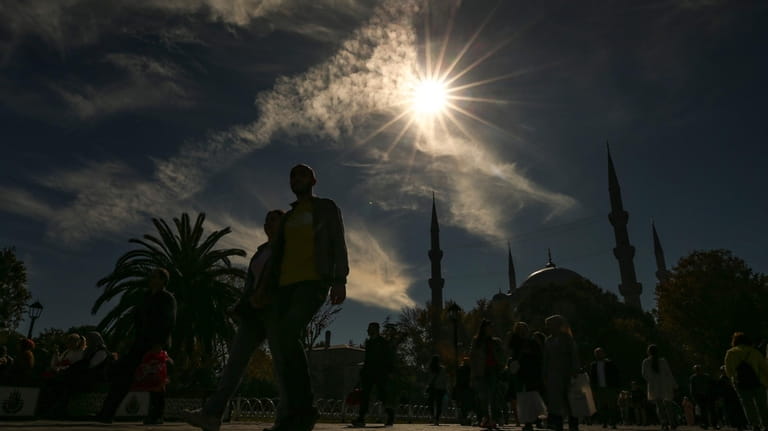 Pedestrians walk near Sultan Ahmed mosque during a partial solar...