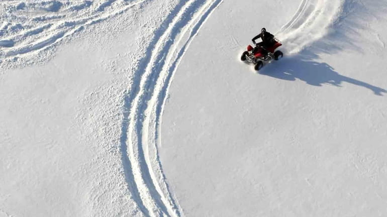 Four-wheelers play in the snow in south Tulsa, Oka. on...