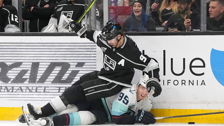 Los Angeles Kings right wing Adrian Kempe, top, falls over...