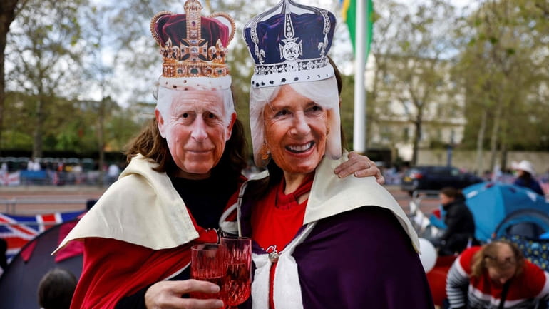 Royal fans wearing masks of King Charles III, left, and Britain's...
