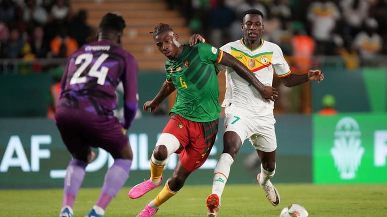 Cameroon's Christopher Wooh, centre, shields the ball as he defends...