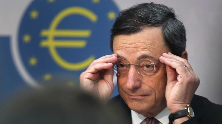 President of European Central Bank Mario Draghi adjusts his glasses...