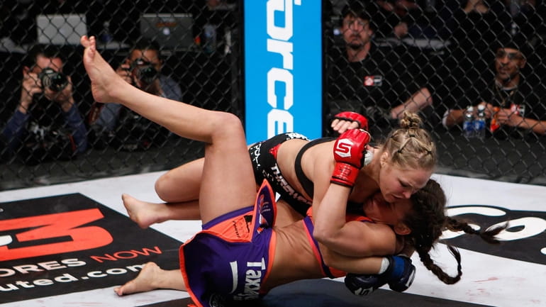 Ronda Rousey, top, and champion Miesha Tate fight for the...