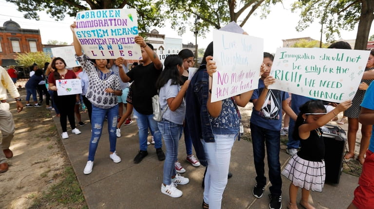 Children of immigrant parents hold signs in support of them...