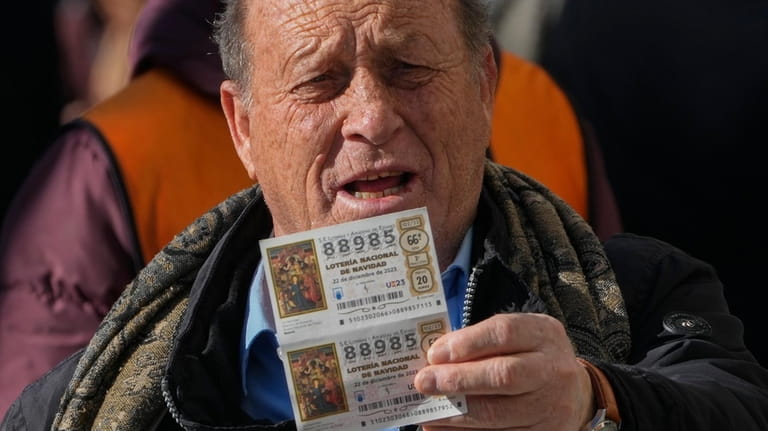 A man holds up a Christmas lottery ticket he is...