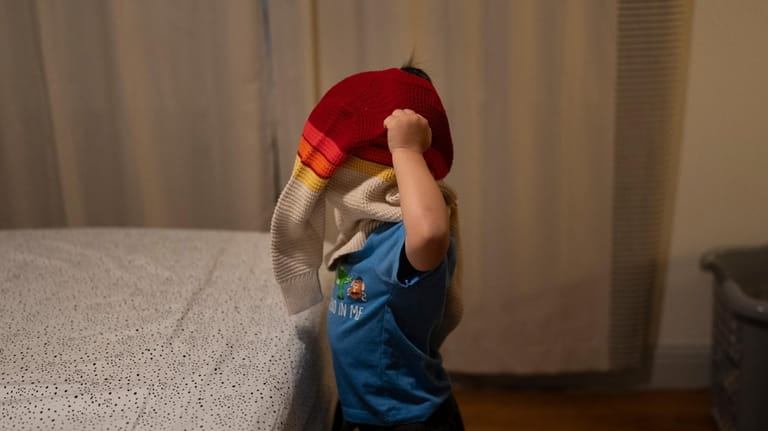 Ethan Quinn, 4, puts on his sweater while getting ready...