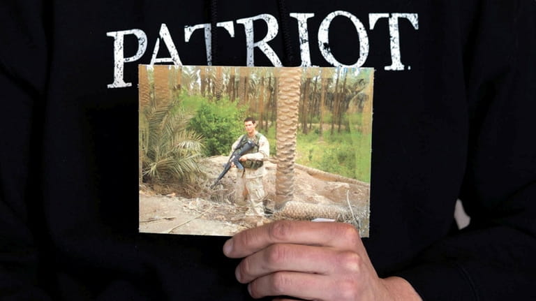 Matthew Schmidt holds a photo of himself as a soldier...