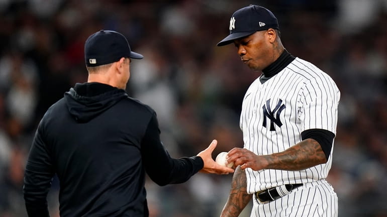 Yankees relief pitcher Aroldis Chapman hands the ball to manager...