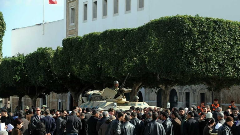 Tunisians gather around a soldiers standing guard in a military...