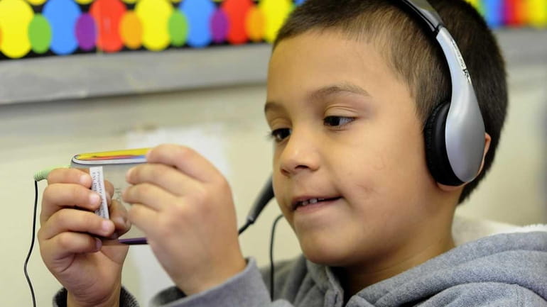 First-grader Christopher Avelar-Sorto, 5, uses an iPod Touch in his...