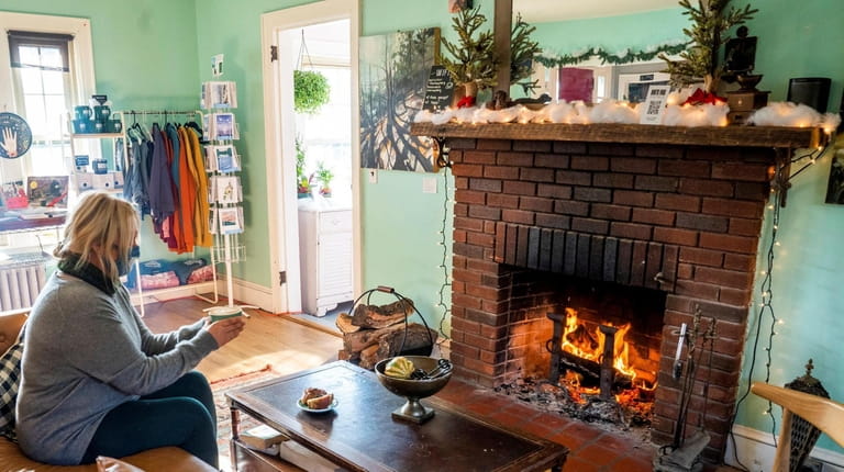Melissa Germano of Southold sits by the fireplace at the...