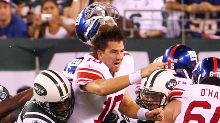 Eli Manning of the Giants loses his helmet after being...