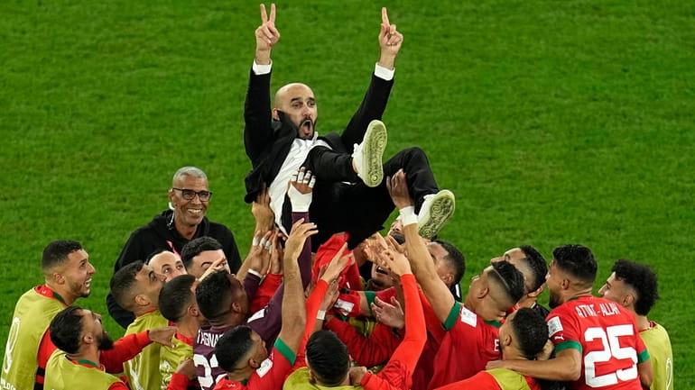 Morocco's head coach Walid Regragui is thrown in the air...
