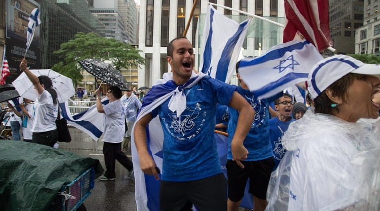 Festive marchers in the Celebrate Israel Parade walk along Fifth...
